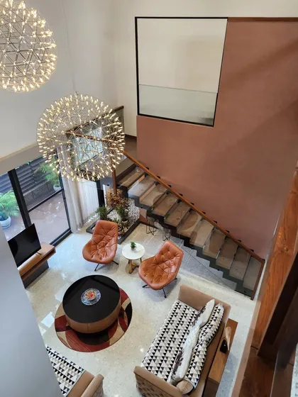 An overhead view of a double-height living room, showcasing the spatial arrangement and the impact of the large, dandelion-like chandeliers. This perspective highlights the open, airy feel and the connection between different levels of the home.