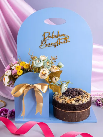 A modern and unique Raksha Bandhan gift set. The focus here is on the innovative packaging, with the cake and gift box presented as a single, beautifully designed unit.