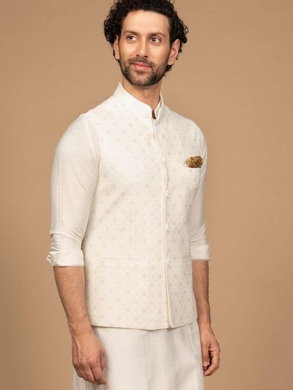 An ivory Nehru jacket with subtle, all-over embroidery. Paired with a matching ivory kurta, this ensemble exudes a timeless charm and refined elegance.