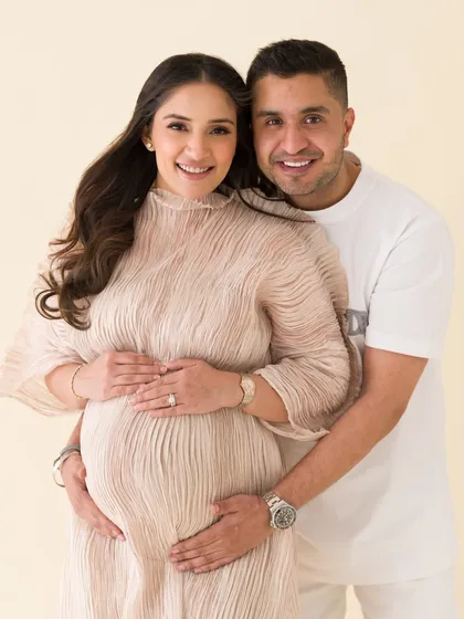 A joyful and classic couple's portrait. Their bright smiles and loving hold on the baby bump make this a perfect snapshot of their happiness.