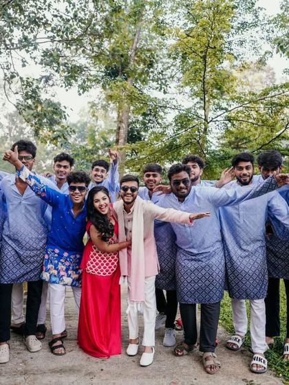 The couple posing with the entire groom's squad, all in coordinated outfits for the Haldi.