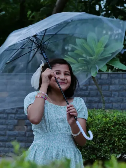 The simple joy of a young girl playing in the rain. I believe in letting kids be kids, and this candid childhood photography captures that spontaneous happiness, using a simple prop like an umbrella to frame the moment.