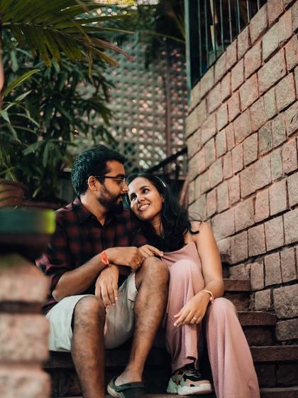 A romantic evening shot of a couple sitting on brick steps, illuminated by the warm glow of a lantern. We use ambient lighting to create a cozy and intimate mood in urban settings.