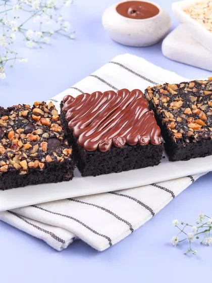 A trio of our decadent eggless brownies. This plate features our popular Nutella Brownie, a healthier Oats Jaggery Brownie, and the classic Walnut Brownie.
