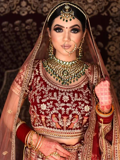 This image showcases the full bridal look, with the velvet lehenga and contrasting green jewellery. A timeless choice for any bride, available for rent.