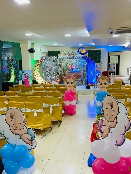 The seating area for a baby shower, with the aisle decorated with cute baby-themed balloon pillars in pink and blue.