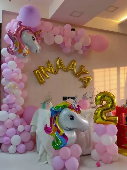 A magical unicorn-themed party for a second birthday. This setup includes a beautiful balloon arch in pastel pink and white, with large unicorn foil balloons to bring the fantasy to life.