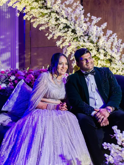 The couple, dressed in elegant evening wear, enjoying their Sangeet. Their outfits perfectly complement the sophisticated, floral-heavy decor.