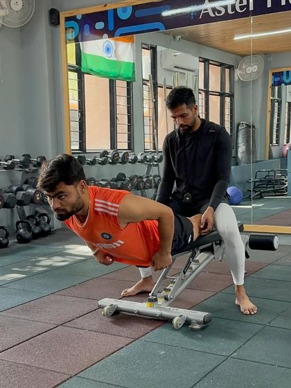 Assisting Rinku Singh with a posterior chain exercise. This hands-on approach helps the athlete feel the correct muscle activation and builds trust between the coach and player.