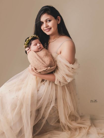 A mother in an elegant gown holding her newborn baby. A beautiful combination of a maternity and newborn feel.