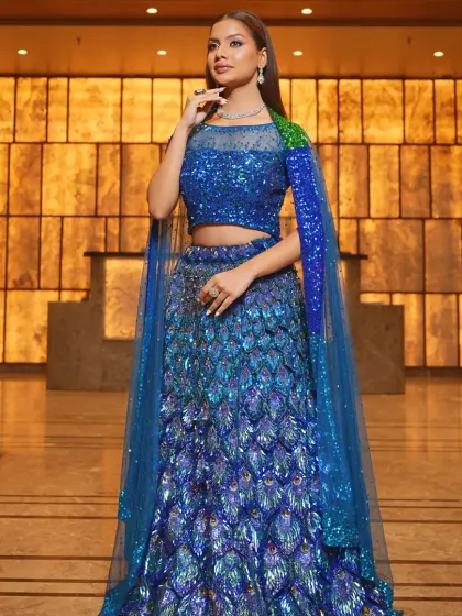 Make a bold statement at your reception or cocktail party with this stunning peacock-inspired lehenga. The vibrant blue sequins and unique design are paired with a delicate diamond-style necklace to create a modern, unforgettable look.