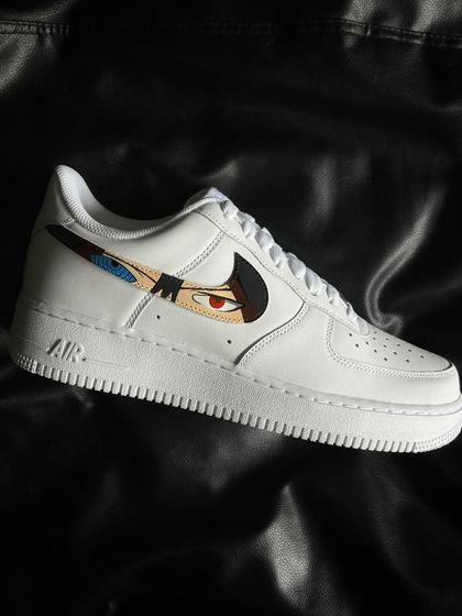 A side profile of the Sasuke custom sneaker, featuring his Rinnegan and Mangekyo Sharingan in the swoosh.