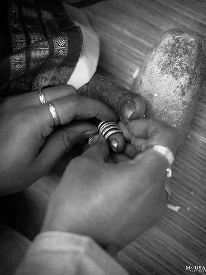 A close-up, black and white shot of the 'Jodi Mettu' or toe ring ritual. This intimate frame highlights a beautiful tradition shared between cultures, symbolizing the start of married life.