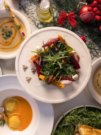A top-down view of our holiday table, featuring a winter salad with arugula and beets, ravioli, and other festive dishes.