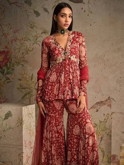 A stunning red printed sharara set, perfect for a festive occasion. The peplum top and flared pants create a flattering and stylish silhouette.
