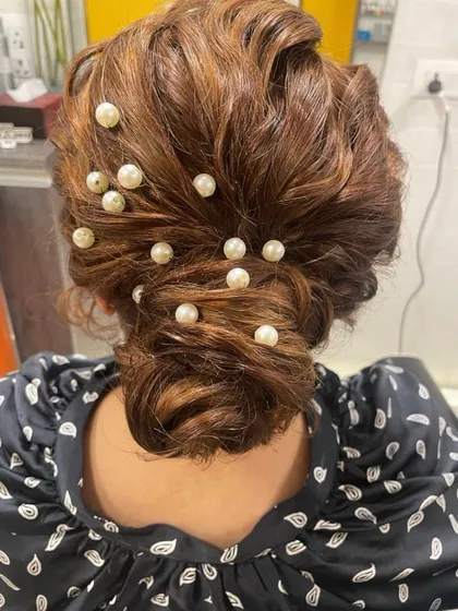 A modern take on a classic bun, this hairstyle is decorated with scattered pearls for a chic and contemporary feel. It's a versatile look that works for both Indian and Western outfits.