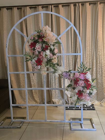 A rustic-chic floral decoration on a white window-pane arch, perfect as a photo booth or backdrop for an intimate event.