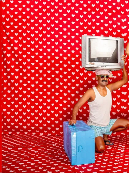 A playful, surreal image from my 'No Longer A Memory' series, featuring a man in shorts and a tank top holding a vintage television over his head against a heart-patterned backdrop.