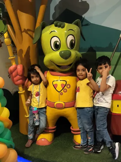 Three happy children give peace signs while posing with the Tinga Dojo mascot.