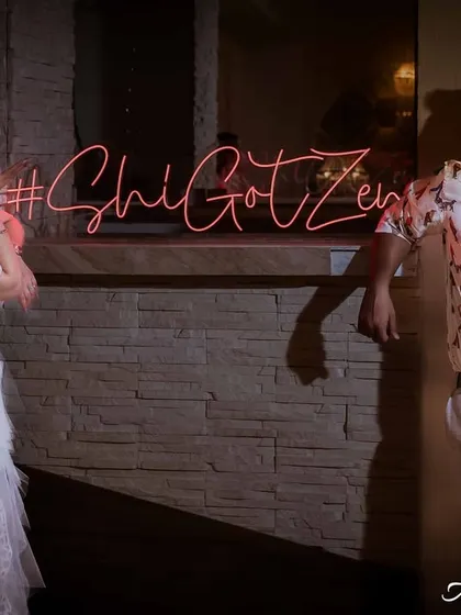 A playful portrait of the couple posing next to their custom neon wedding hashtag. This is a fun way to incorporate personal details into your event photography.