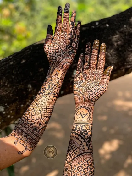 This full-arm bridal henna for Anuja features her and her partner's initials, S and A, elegantly placed within the design. The combination of bold patterns and fine details makes it stand out.