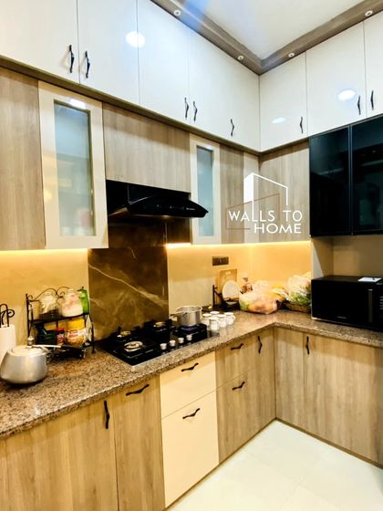 A practical and stylish kitchen design with a mix of wood-finish and solid color cabinets. The space is well-lit with under-cabinet lighting and features a granite countertop.