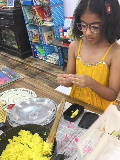 A young participant carefully crafting her modak. This hands-on activity is a delicious way to learn about festival traditions.