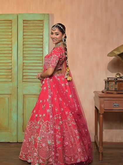 A side view of a model in a pink lehenga, showing the beautiful braid and hair accessories that can be paired with my rental outfits.