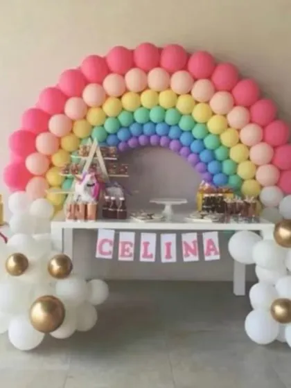A beautiful rainbow balloon arch over a dessert table. This is a perfect, cheerful theme for any child's party.
