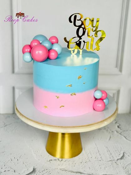 Boy or Girl? A classic gender reveal cake with pink and blue halves, decorated with a cascade of matching spheres and a golden topper.