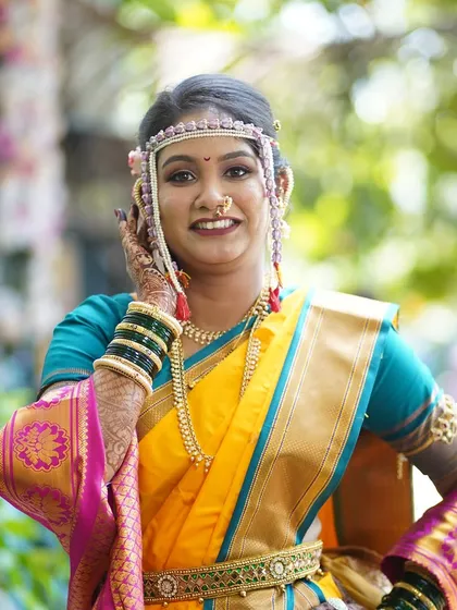 A confident and happy bride posing for the camera. The full look, including the kamarband and expertly draped saree, is showcased here.