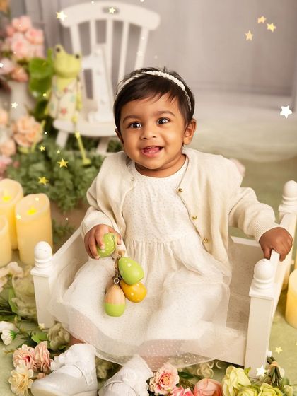 A moment of play during a first birthday session. This photo captures the baby's delight as she interacts with toys in a beautifully styled, floral-themed set.