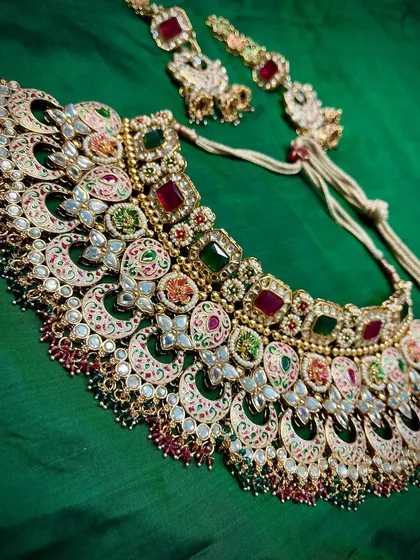 A flat lay of one of our colorful Meenakari sets. You can see the statement necklace and matching maang tikka, ready to be rented for your big day.