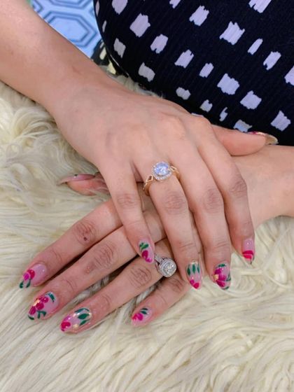 A beautiful set of almond-shaped nails featuring hand-painted pink and red floral art. The design is perfect for clients who love a touch of romance and color.