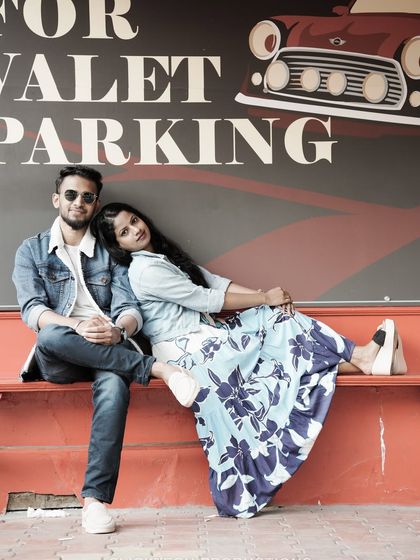 A cool, relaxed pose on a bench in front of a 'Valet Parking' sign, giving off a modern and casual vibe.