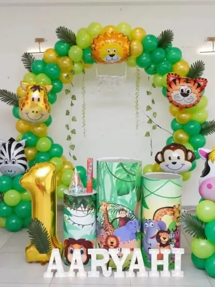 A jungle-themed first birthday party with a circular balloon arch, animal character foils, and a large '1' balloon.