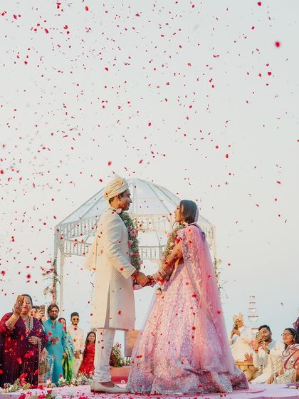 A stunning beachside Varmala ceremony at sunset in Goa, with a shower of petals creating a truly magical atmosphere.