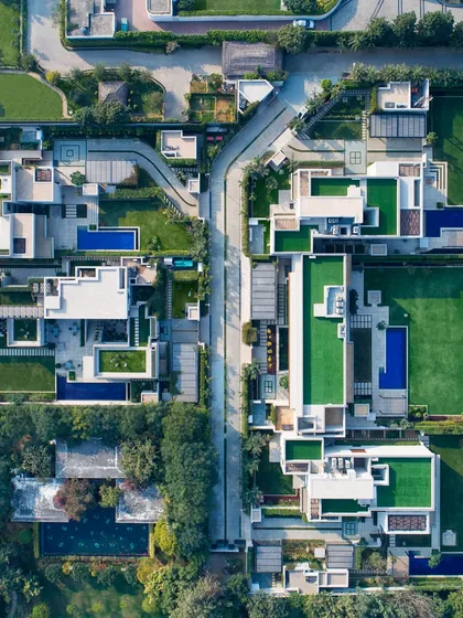 This drone photograph shows a cluster of five sister homes we designed to balance privacy with a connection to nature. Each Vastu-compliant home opens into its own green landscape with pools and rooftop gardens, creating a private oasis within a cohesive micro-community.