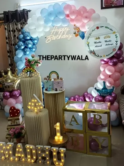 A unique half-and-half balloon arch for a twins' birthday. One side is blue and the other is pink, with crowns for the little prince and princess.