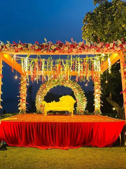 The fully lit outdoor mandap at night, showcasing the beautiful combination of warm lights and colorful floral decorations.