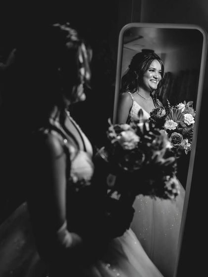 A beautiful black and white shot of the bride looking at her reflection with a smile. This is a classic and happy getting-ready moment.