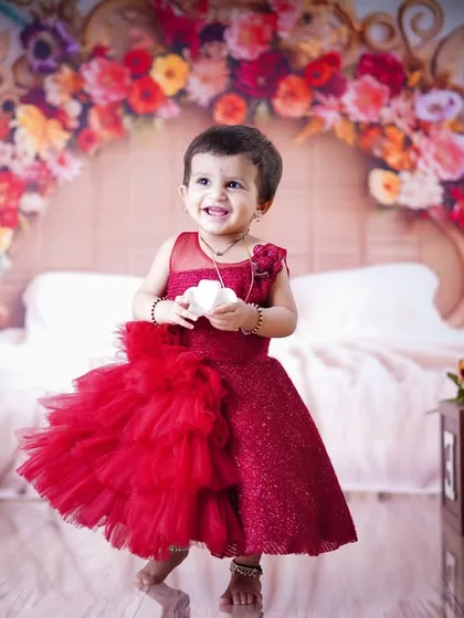 A boho-chic birthday celebration. This little girl in a red dress is all smiles in our "Boho Living" setup at the Vashi branch, featuring a stunning floral headboard.
