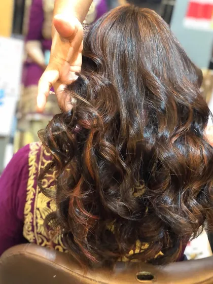 These highlights are a mix of caramel and lighter brown tones, creating a rich, multi-dimensional effect. The bouncy curls really make the different shades pop.