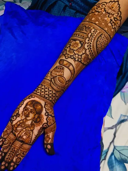 The bride's full arm design for her Maharashtrian wedding. The portrait is complemented by floral patterns and traditional symbols, creating a cohesive and stunning bridal look.