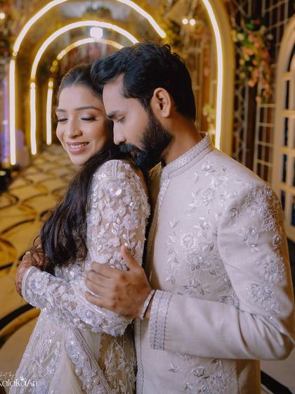 A warm and loving embrace in a beautifully lit hallway. The bride's happy expression is the highlight of this photo.