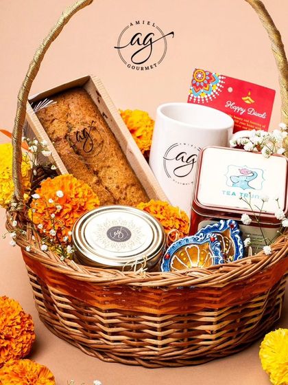 This festive Diwali basket is a wonderful gift, featuring a tea cake, an AG mug, a tin of tea, and other gourmet goodies, all nestled amongst fresh marigolds.