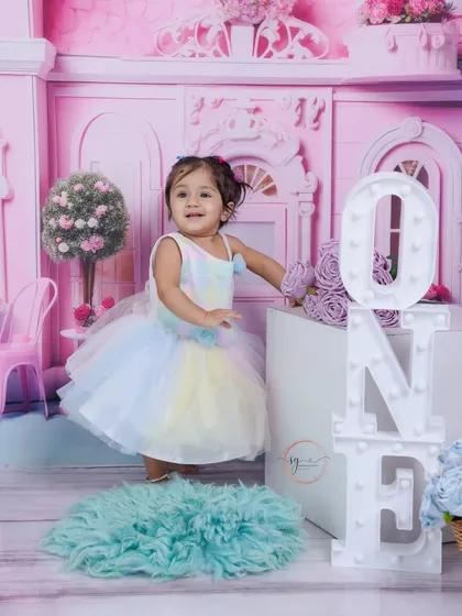 Standing by the light-up "ONE" blocks, this portrait celebrates her big milestone in a dreamy, pastel-colored studio setting.