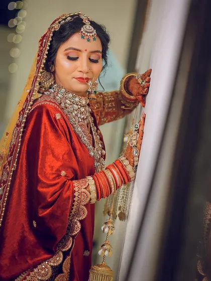 A candid-style pose against a simple wall, highlighting the rich texture of the velvet wedding outfit.