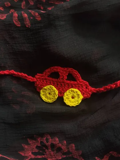 A simple yet charming red car crochet rakhi. This design is great for young kids who love vehicles and makes for a fun, playful thread of protection.