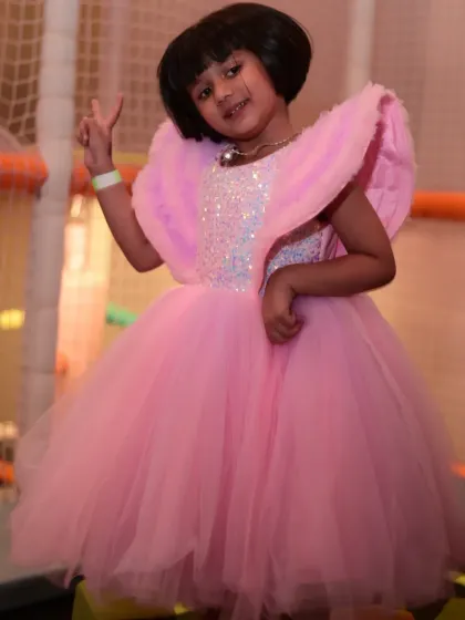 A birthday girl in her beautiful pink angel-wing dress, ready to celebrate.